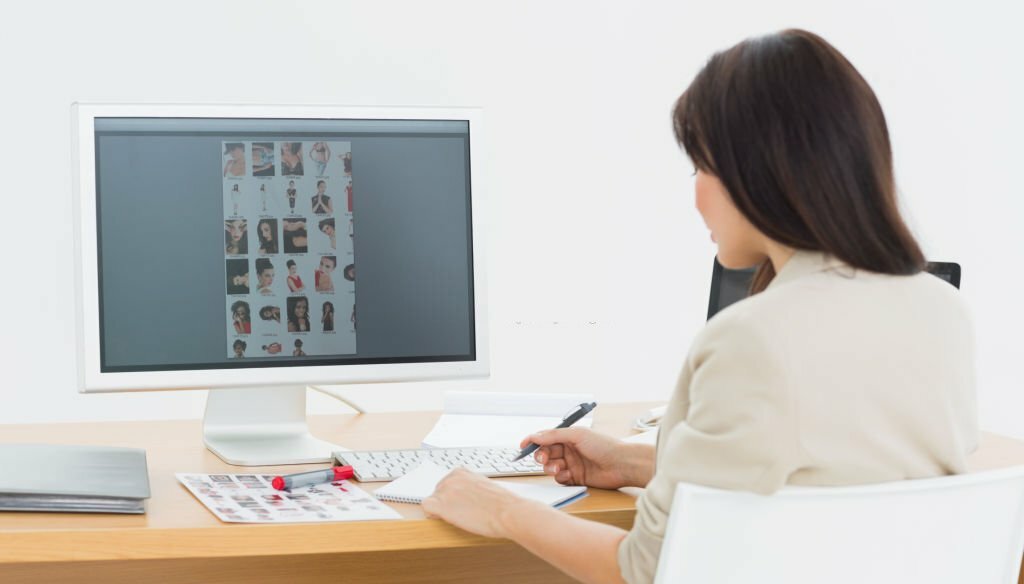 Rear view of a female artist sitting at desk with computer in the office